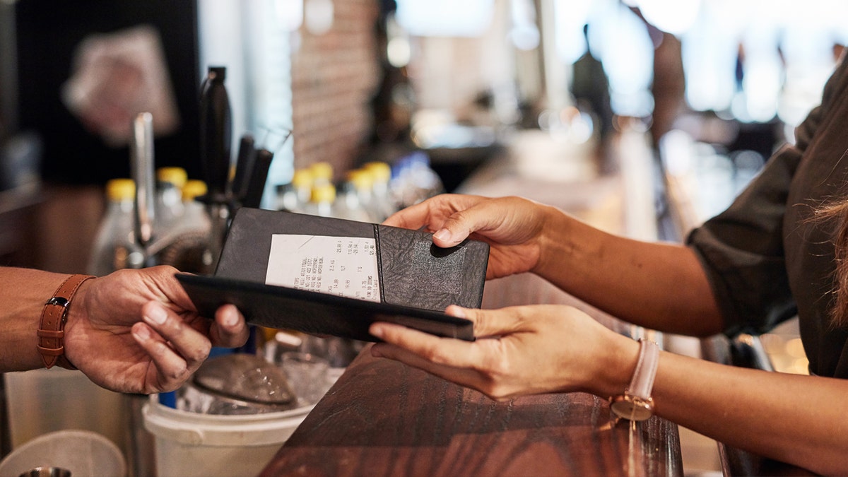 Woman gets handed a receipt at bar.