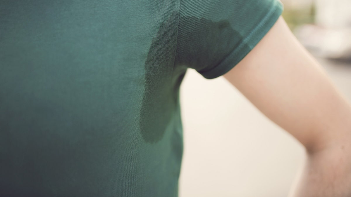 Close up of a person's sweaty underarm with pit stains on shirt.