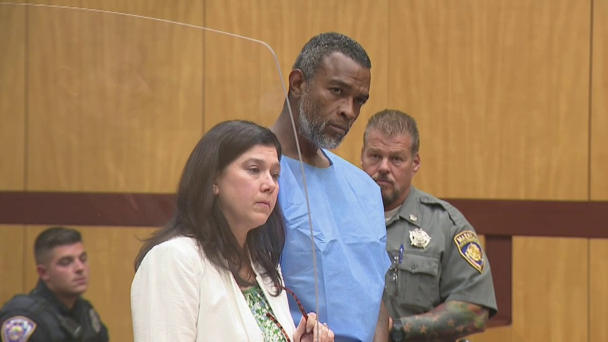 Winston Tate in blue jumpsuit with lawyer in court