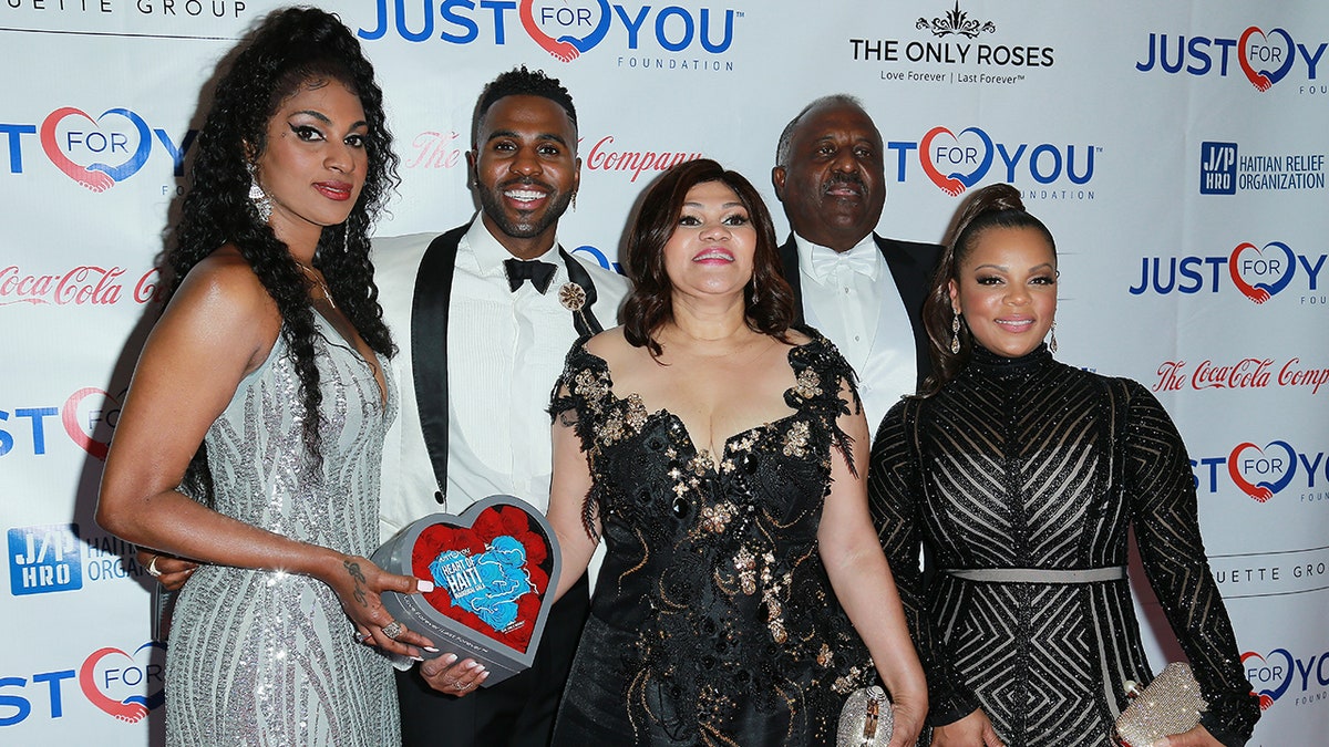 Jason Derulo in a white tuxedo poses with members of his family at the "Heart of Haiti" Gala in 2018