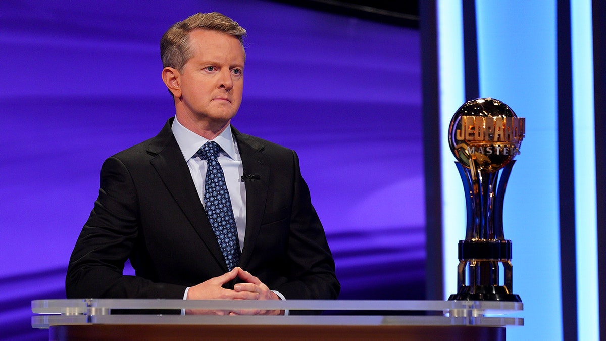 Ken Jennings looks serious with his hands together behind the podium during "Jeopardy"