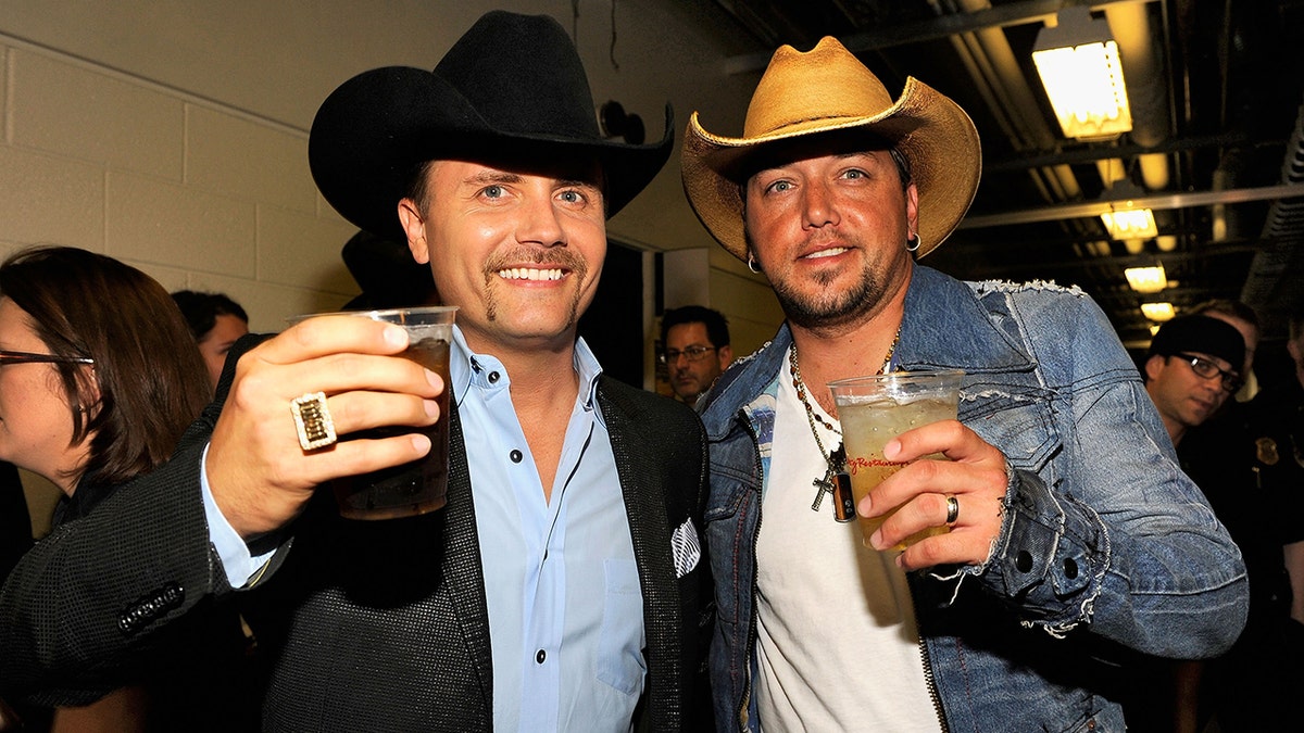 Jason Aldean and John Rich wear cowboy hats and toast backstage