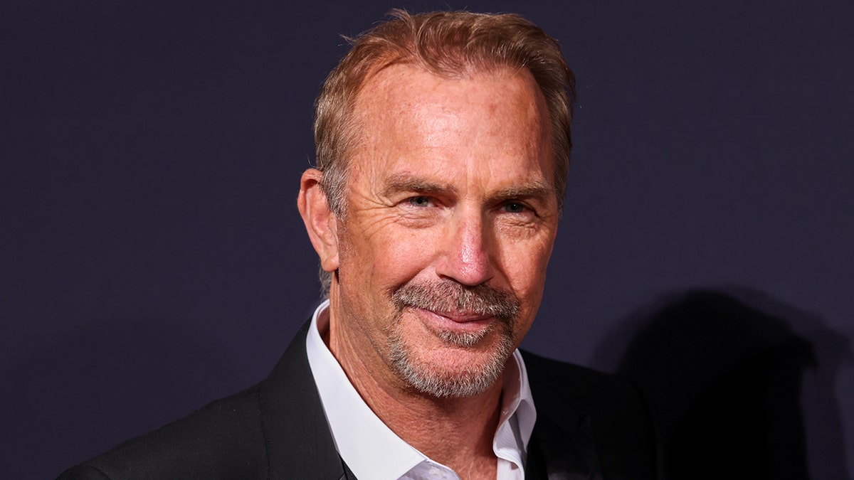 Kevin Costner cammina sul tappeto rosso indossando un completo