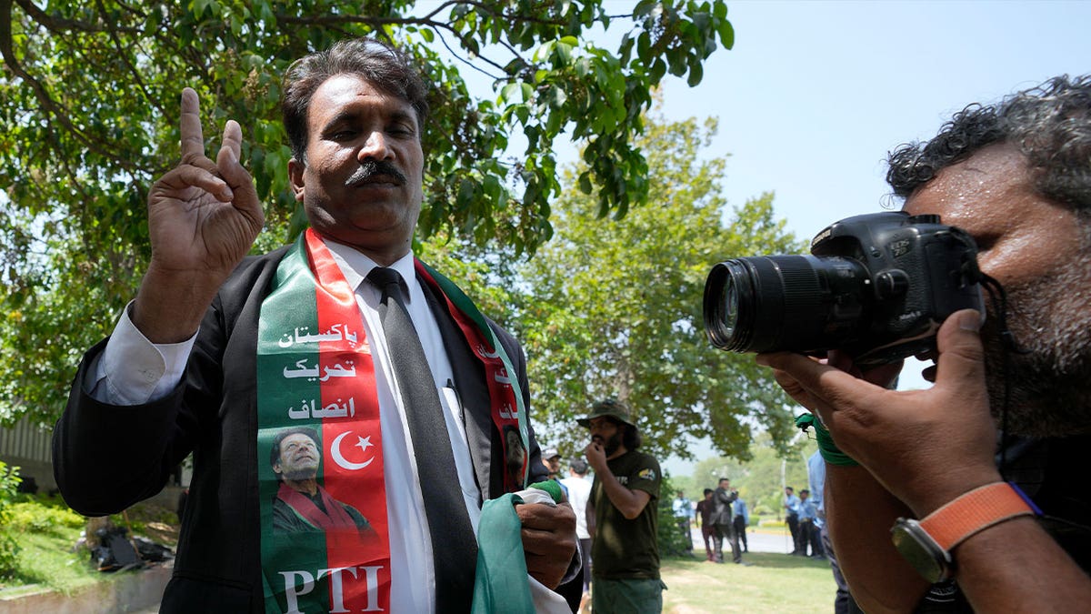 man holds victory sign in front of photographer