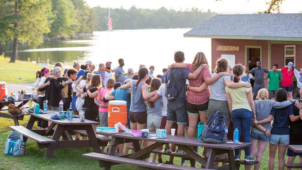 Group shot of Camp Kita's campers linked in arms in a circle