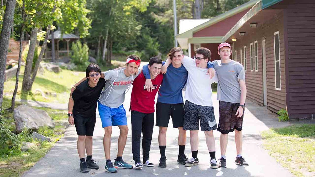 Group of six male Camp Kita campers posing for a picture outside their cabin