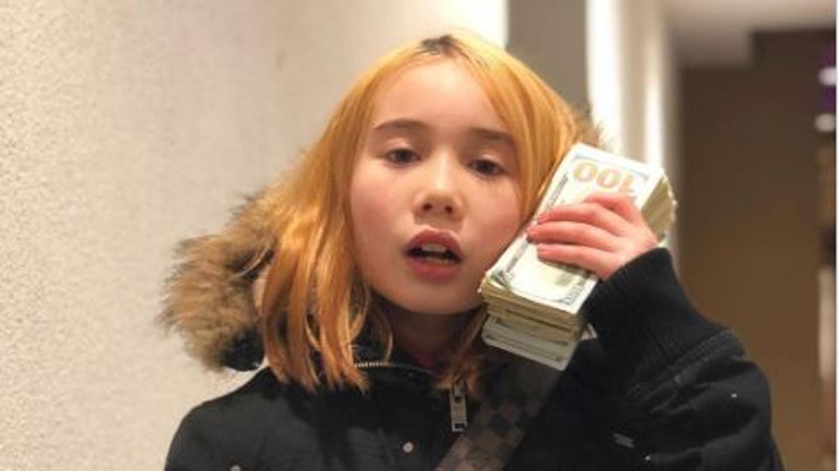 Lil Tay holds $100 bills and wears Louis Vuitton purse
