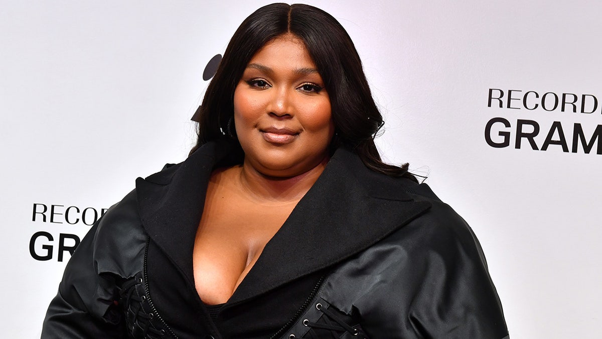 Lizzo smiles at The GRAMMY Museum in Los Angeles in a black low-cut outfit