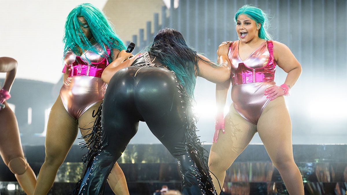 Lizzo on stage in the UK with her dancers with her butt facing the crowd