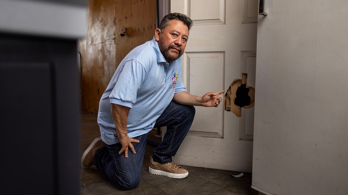 North Hollywood print shop owner Carlos Pena points to damaged door