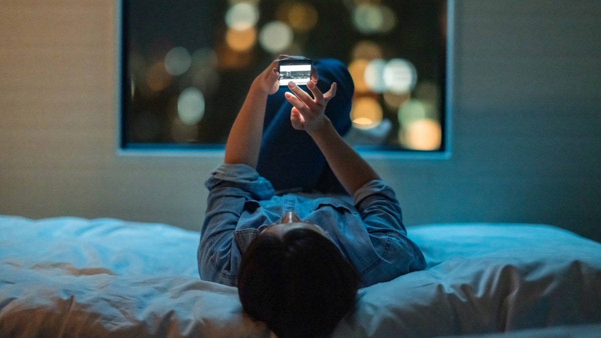 Man on phone lying in bed