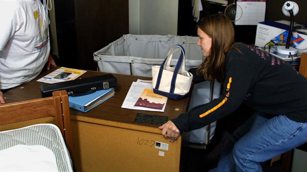 A student moving furniture around her college dorm