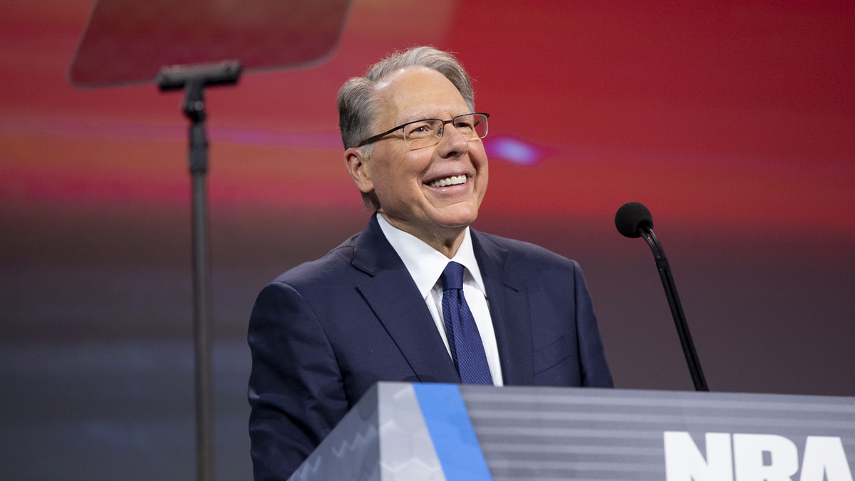 NRA CEO Wayne LaPierre behind lectern smiling