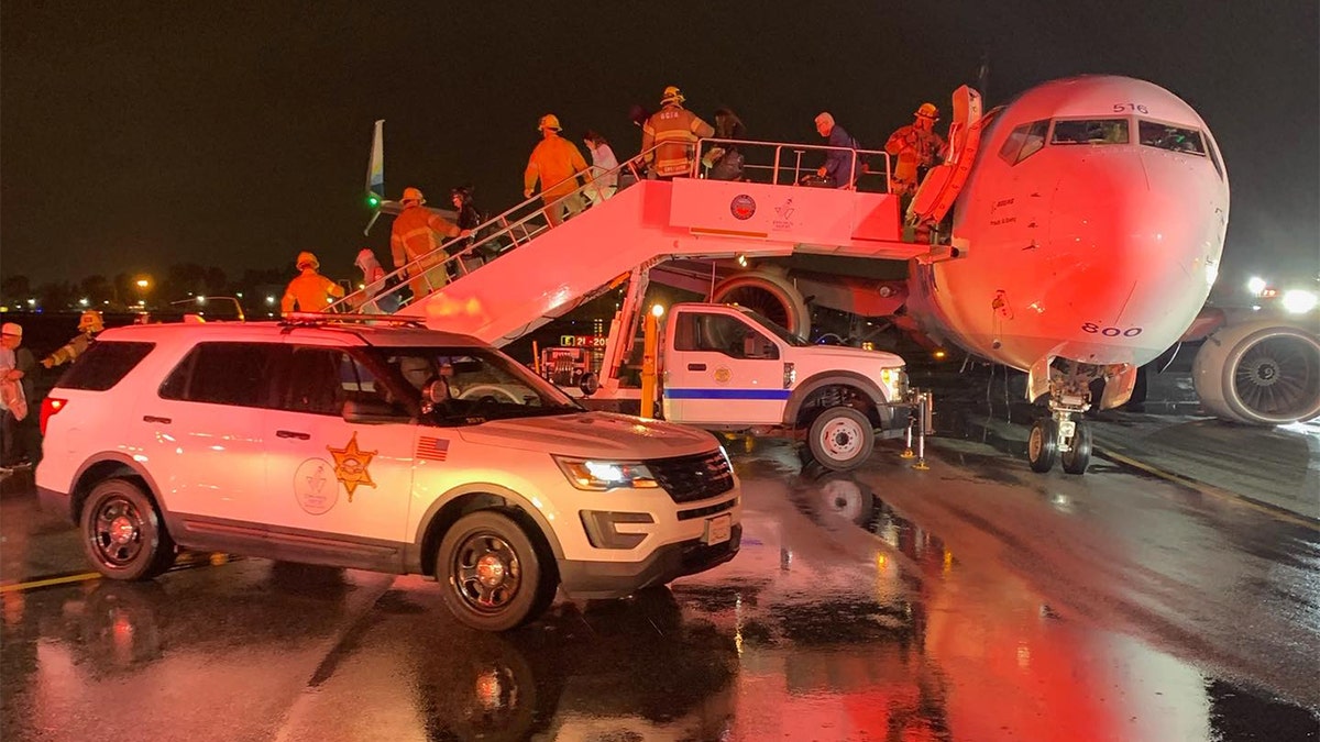 Firefighters guide passengers of an Alaska Airlines plane