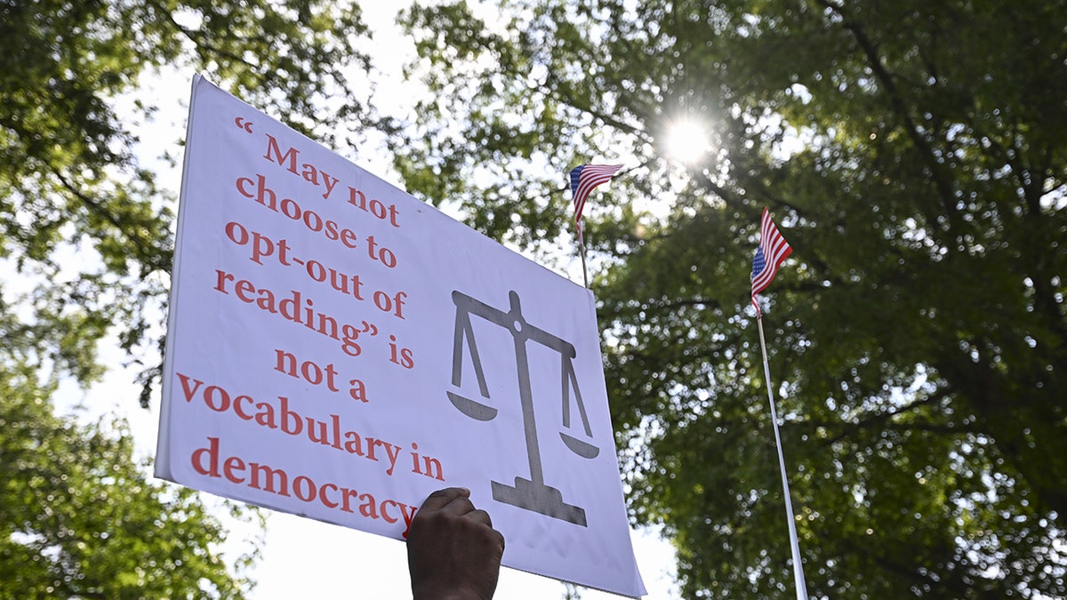 A protest sign reads, "'May not choose to opt-out of reading' is not a vocabulary in democracy"
