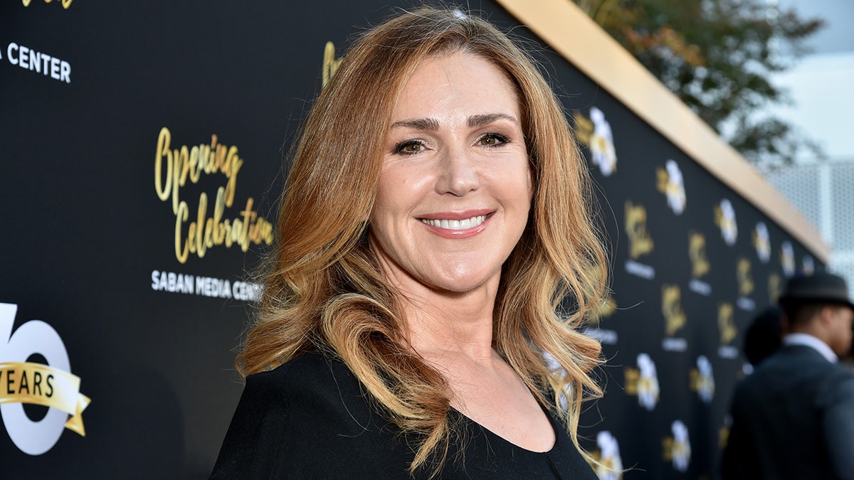 Peri Gilpin smiles on the carpet in a black dress