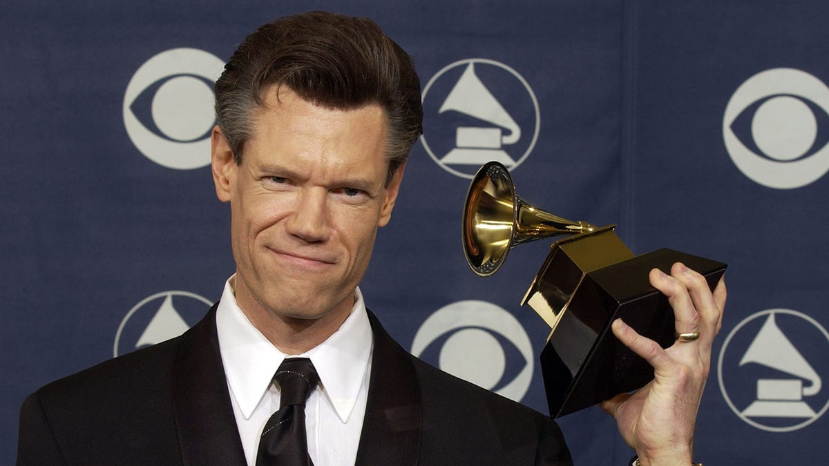 A photo of Randy Travis posing with his Grammy Award in 2004