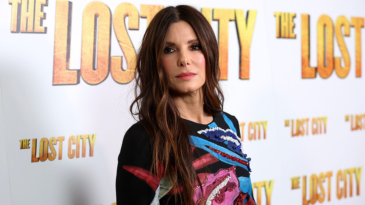 Sandra Bullock in a black dress with many color swatches on the front at "The Lost City" premiere