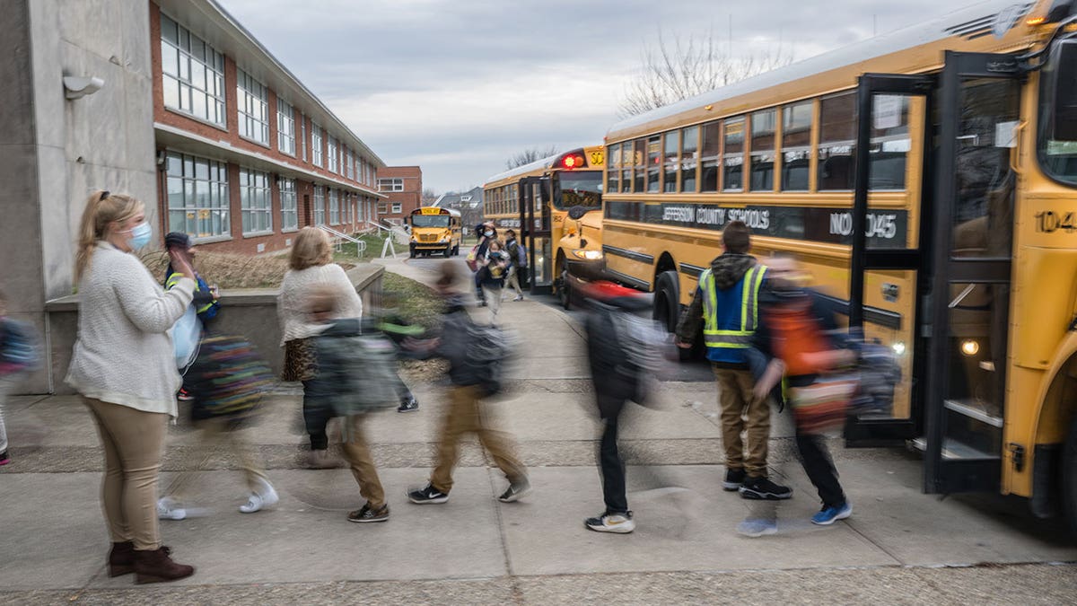 teacher waves to her students near buses