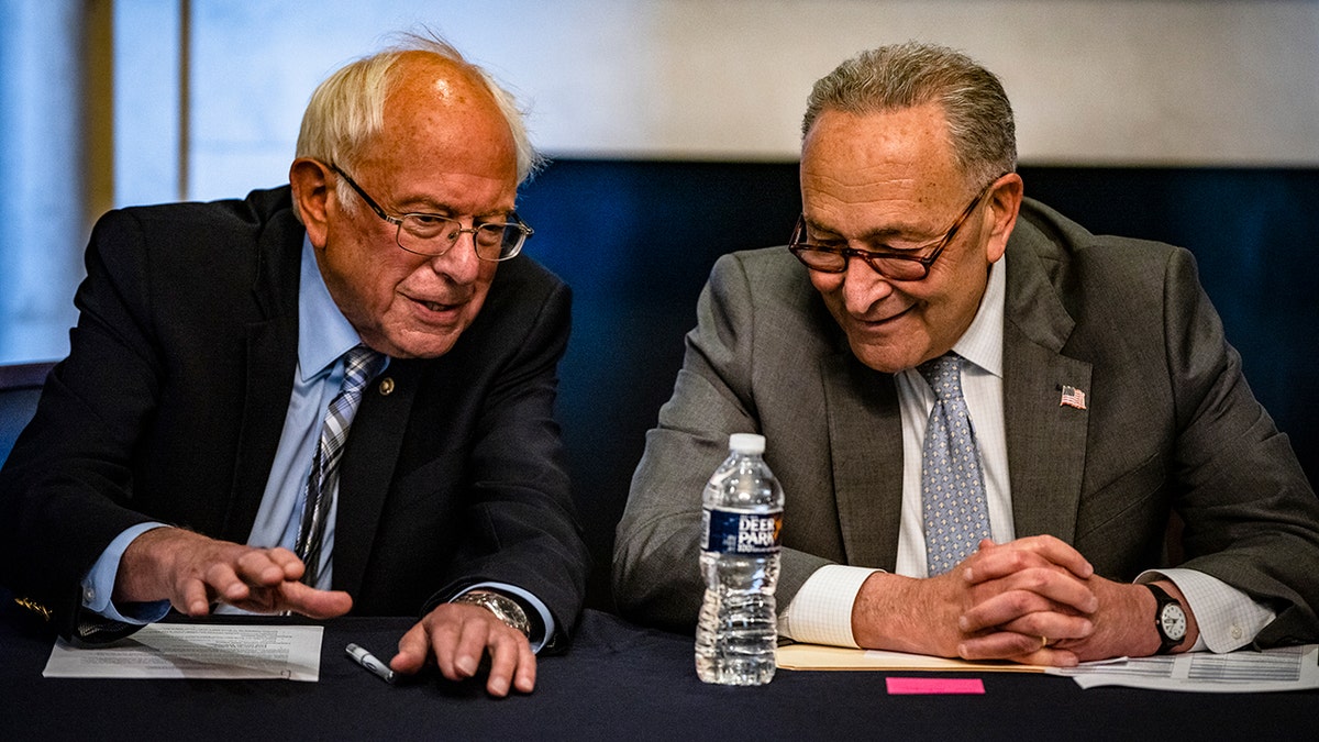 Senators Bernie Sanders and Chuck Schumer sit together at a table