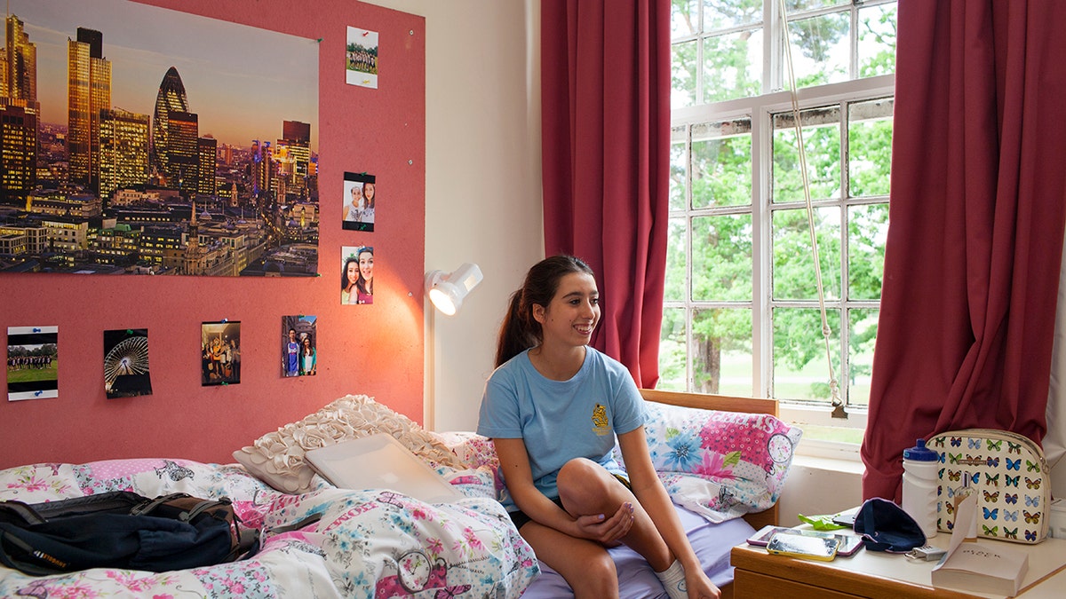A college student sitting in her decorated dorm room