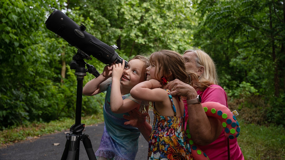 Three people using a telescope