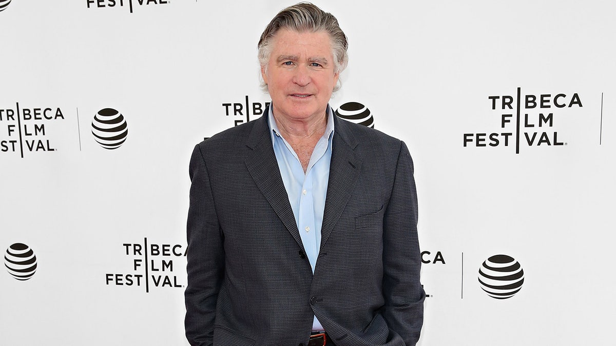 Treat Williams in a dark suit on the carpet