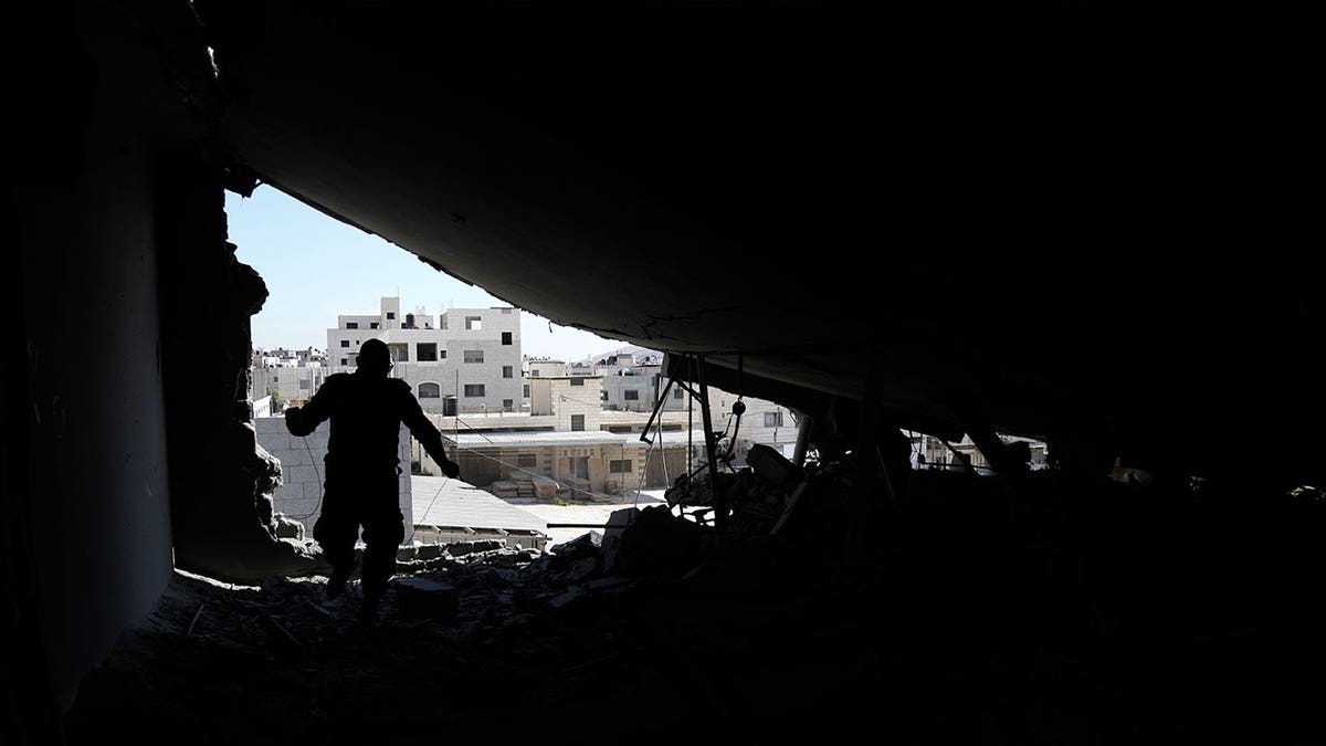 Palestinian engineer inspects a demolished home