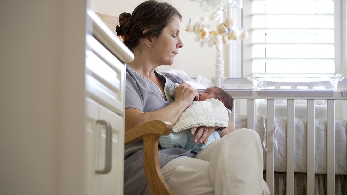 Woman in rocking chair feeds baby