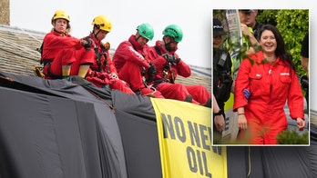 Greenpeace climate protesters climb atop UK prime minister's home, hang black fabric