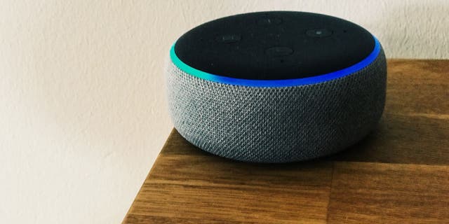 A gray Amazon Alexa device on a wooden table