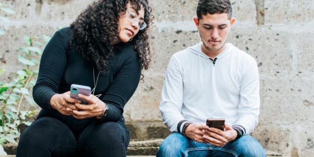 Woman looking at a man's phone while he's on it.