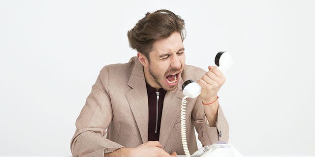 Stock image shows man yelling at telephone