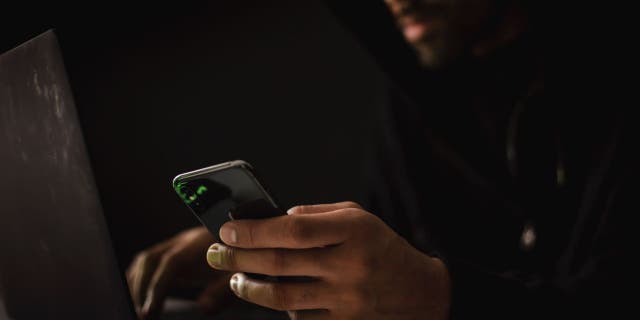 Computers user types while holding smartphone