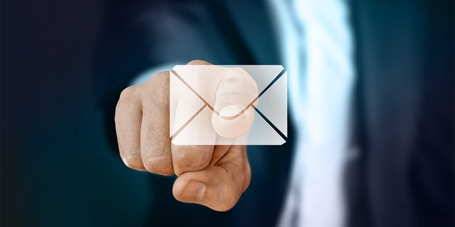 A man wearing a suit pointing his finger at a semi-clear email envelope on the screen