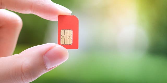 Photo of a person holding up a SIM card.