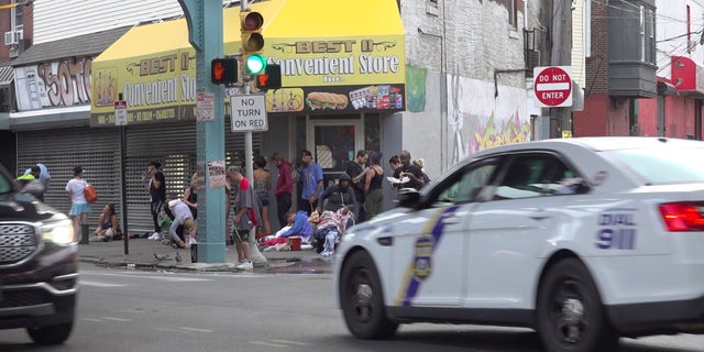 Police car drives past drug users in Kensington