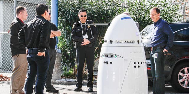 Photo of police officers and a robot security guard.