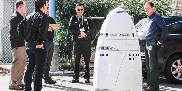 Polis memurları ve bir robot güvenlik görevlisinin fotoğrafı.