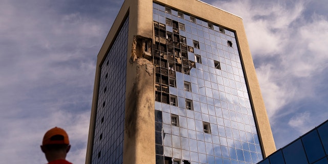 Maintenance worker looks at damaged building in Kyiv