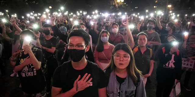Demonstrators hold their cellphones 