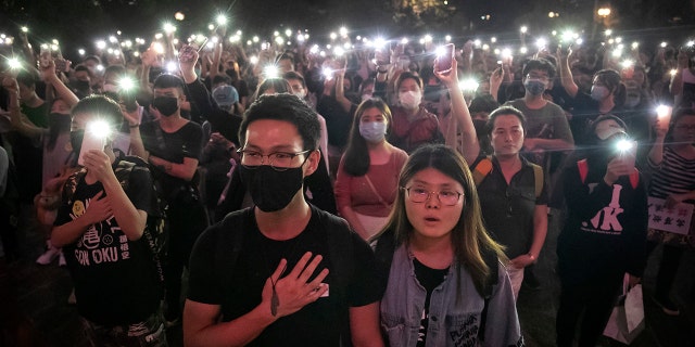 Demonstrators hold their cellphones 