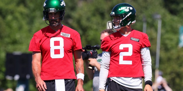 Aaron Rodgers and Zach Wilson look on