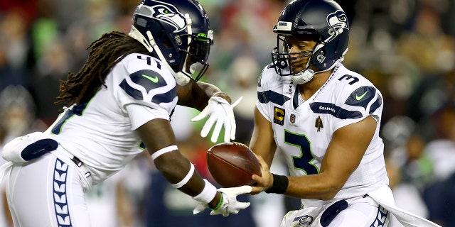 Russell Wilson hands the ball off to Alex Collins