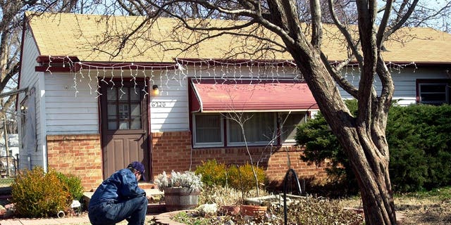 Man crouching in front of the house