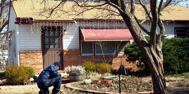 Man crouching in front of the house