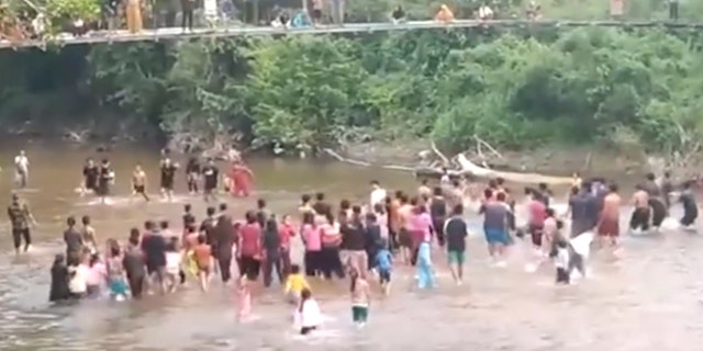 People on a bridge and in the water in Indonesia