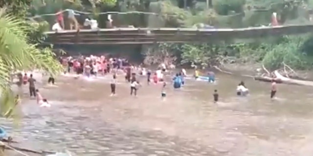 A bridge with people starts to collapse above people in the water in Indonesia