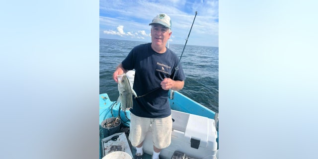 Man holds up half-eaten fish.