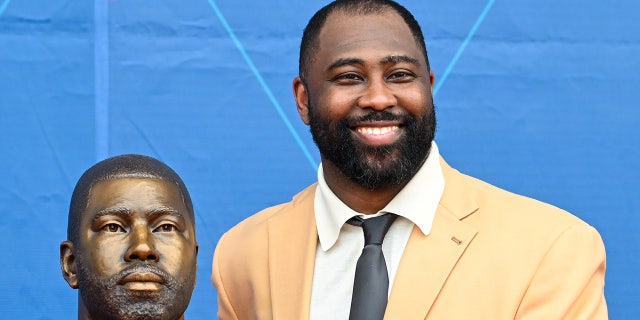 Darrelle Revis smiles next to bust